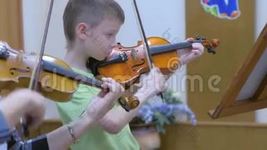 在<strong>音乐学校</strong>的<strong>音乐</strong>课上，小男孩学生和老师一起拉小提琴。